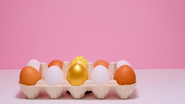 彩色复活节彩蛋在纸板箱里.粉色背景上的彩蛋. — 图库视频影像