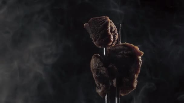 4k Fork with pieces of delicious barbecued meat on black background — Stock Video