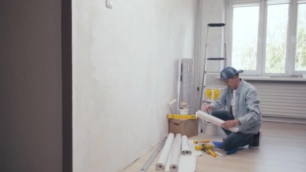 Мужчина показывает обои инструменты, на камеру, что означает, что он готов к работе — стоковое видео