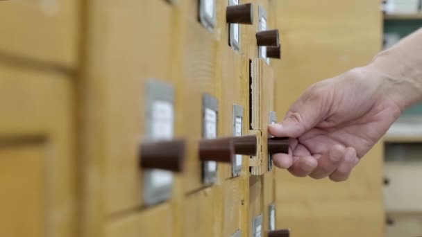 4K. Catálogo de tarjetas en la biblioteca. Un hombre está buscando información en un archivador. — Vídeo de stock