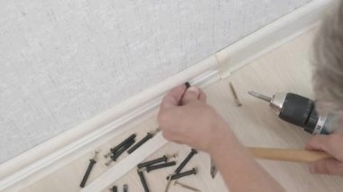 Adam duvardaki kaide montajı üzerinde çalışıyor. Evdeki oda tadilatı