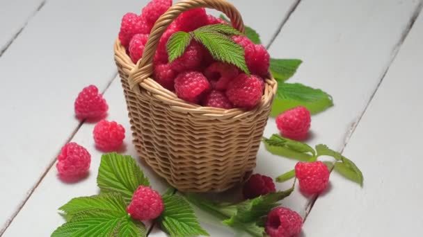 4K. Framboises mûres dans un panier en osier rotation une table en bois blanc — Video