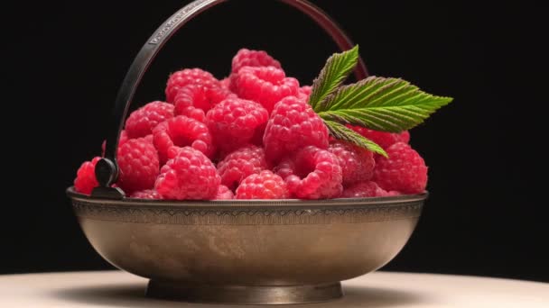 4K. Reife Himbeeren in Vintage-Metallschale Drehung auf schwarzem Hintergrund. — Stockvideo