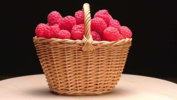 4K. Framboises mûres dans un panier en osier tourner sur un fond noir — Video