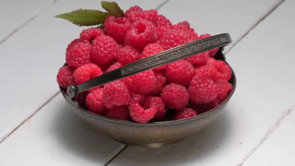 4K. Ripe raspberries in vintage metal bowl rotation on a white wooden table. — Stock Video