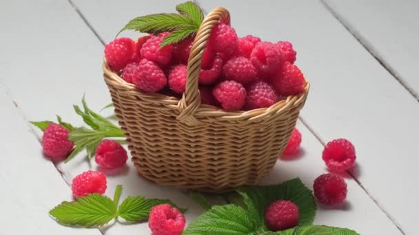 4K. Framboises mûres dans un panier en osier rotation une table en bois blanc — Video