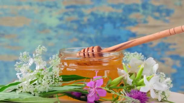 4k.O frasco de vidro com mel fresco gira lentamente sobre o fundo rústico. — Vídeo de Stock