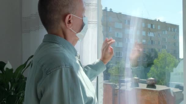 Oudere man op zelf-isolatie kijkt naar de straat door het raam van het huis — Stockvideo