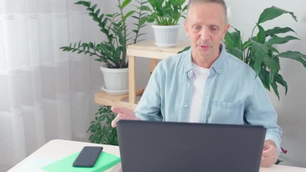 Blogueiro masculino senta-se na mesa na frente do laptop olhar para a tela do PC — Vídeo de Stock