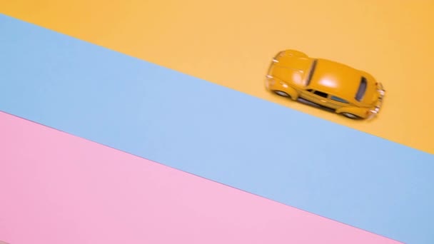Pequenos carros de brinquedo retro vintage em um fundo rosa, amarelo e azul. — Vídeo de Stock