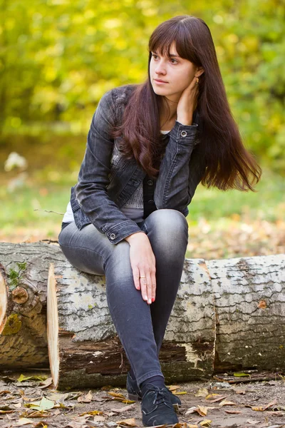 Mädchen sitzt auf einem gefällten Baum — Stockfoto