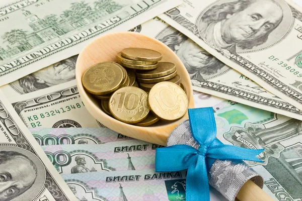 Colher de madeira com moedas em um fundo de dinheiro — Fotografia de Stock