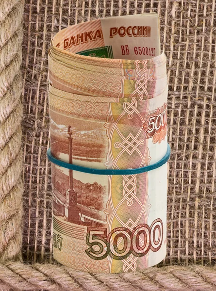 Russian rubles rolled into a tube on a background of burlap — Stock Photo, Image