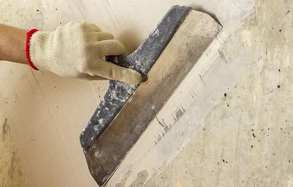 Proceso de masilla pared de hormigón con una espátula de metal — Foto de Stock