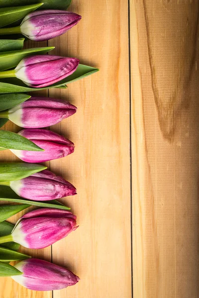 Růžové tulipány na dřevěném stole — Stock fotografie