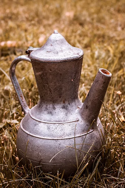 Old metal pitcher on yellow grass — Stock Photo, Image