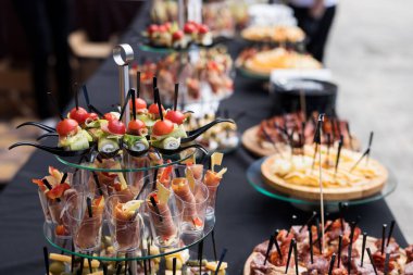 Siyah masalı bir ziyafette bir çift kanepe ve atıştırmalık. Yemek standında domates, salatalık, zeytin, peynir, ekmek ve sosis dilimleri