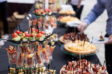 Siyah masalı bir ziyafette bir çift kanepe ve atıştırmalık. Yemek standında domates, salatalık, zeytin, peynir, ekmek ve sosis dilimleri
