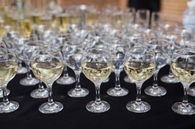 Masanın üzerinde, sığ bir alan derinliğinde şampanya kadehleri yakın plan. Beyaz şaraplı siyah ziyafet masası.