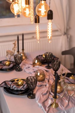 Kutlama masasını boş şarap bardakları ve altın kapaklı siyah tabakla kapatın. Noel ve Yeni Yıl kavramı