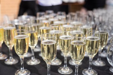 Masanın üzerinde, sığ bir alan derinliğinde şampanya kadehleri yakın plan. Beyaz şaraplı siyah ziyafet masası.