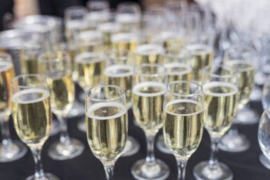 Masanın üzerinde, sığ bir alan derinliğinde şampanya kadehleri yakın plan. Geçmişe dönük beyaz şaraplı siyah ziyafet masası