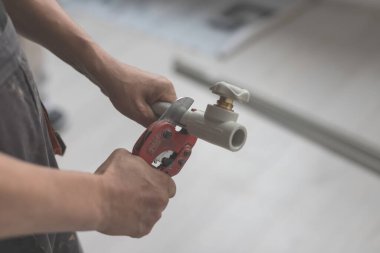 Kırmızı makasla yakın plan çek ısıtma için boruları kes, ya da su kaynağını. Arka planı bulanık polipropilen boru.