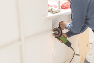 Adam öğütücü kıvılcımlarıyla boru kesiyor. Öğütme makinesiyle çalışma sürecinin yan görünümü