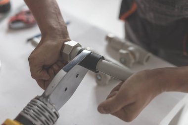 Adam polipropilen için demir lehimlemeye devam ediyor. Sarı ütülü el manzarası ve ısıtma için borular ya da su kaynağı