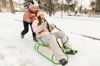Gülümseyen oğul, kış havasında annesine kayıyor.