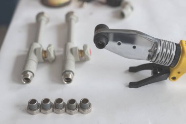 Polipropilen için lehimleme demiri ve beyaz masaya dokunmuş polipropilen boru.