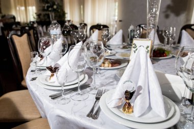 Şarap kadehleri, taze çiçekler ve numaralı masalarla şenlik masalarını kapatın.