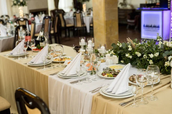 Primo piano della tavola festiva con bicchieri di vino, fiori freschi sulla tovaglia beige — Foto Stock