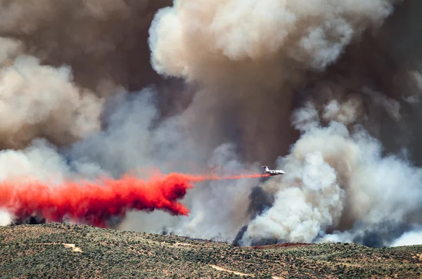 Aviones blancos dejando caer el fuego retardante, ya que combate el fuego salvaje furioso Fotos de stock