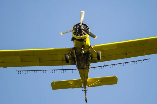 Avion de dépoussiérage des cultures jaunes volant dans un ciel bleu — Photo