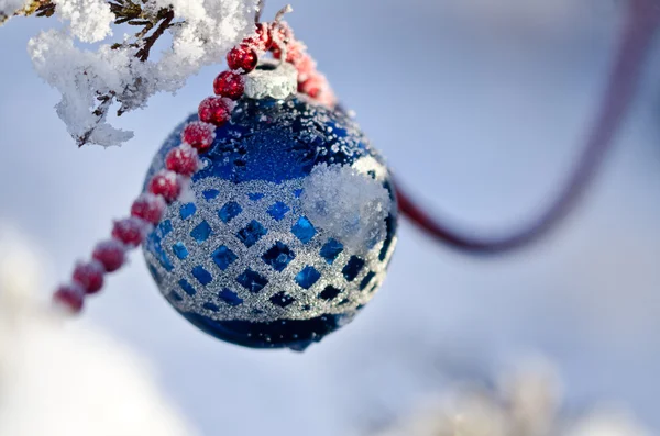 Μπλε χιονοσκέπαστο χριστουγεννιάτικο στολίδι να κρέμεται από ένα δέντρο εξωτερική — Φωτογραφία Αρχείου