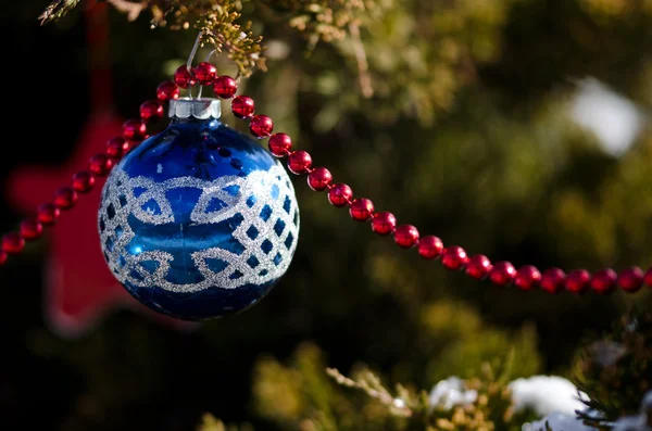 Μπλε κόσμημα κρέμεται από ένα υπαίθριο χριστουγεννιάτικο δέντρο — Φωτογραφία Αρχείου