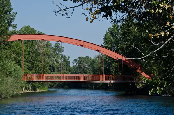 Puente rojo que se extiende sobre el río — Foto de Stock