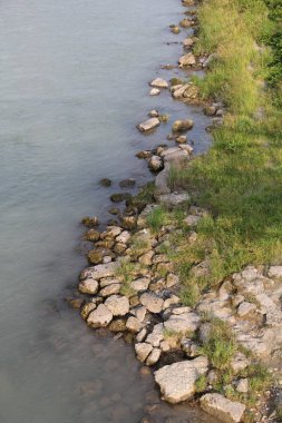Çimen ve taşlarla kayalık nehir kıyısı
