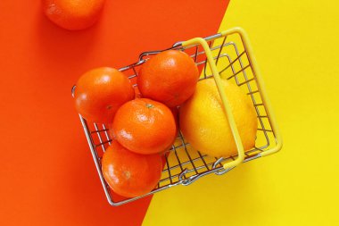 Mandalina ve limon iki renkli arka planda bir alışveriş sepetinde, portakal sarısı arka planda metal sepet, sebze ve meyve, vejetaryen gıda seti satın alınmasını sağlar.