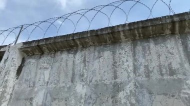 Hapishane duvarındaki dikenli teller gökyüzünün arka planına karşı. Özgürlüklerin kısıtlanması.