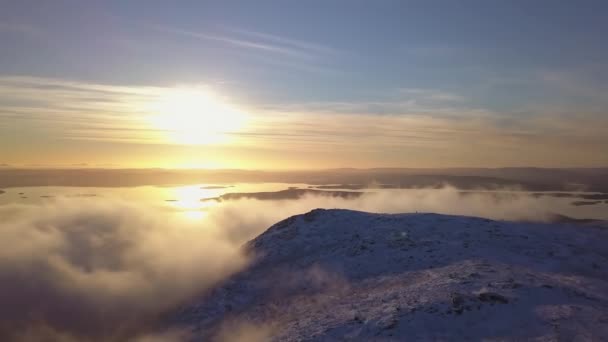 山の上の低い雲と遠くの白い海の間の太陽の下で冬の日に飛ぶ — ストック動画