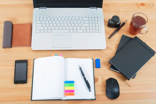 Pracoviště úřadu s notebookem, chytrý telefon a notebook na dřevěný stůl — Stock fotografie