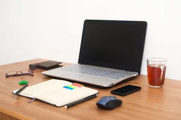 Ofis işyeri dizüstü bilgisayar, akıllı telefon ve ahşap masa üstünde defter — Stok fotoğraf