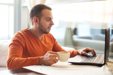 Düşünme, kafede kahve tadını çıkarırken defter üzerinde çalışan yakışıklı genç adam