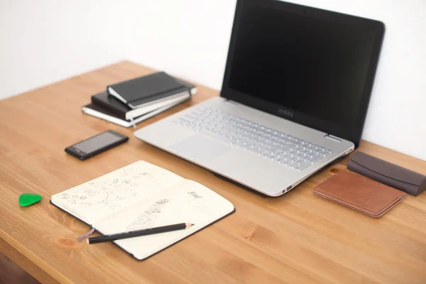 Ofis işyeri dizüstü bilgisayar, akıllı telefon ve ahşap masa üstünde defter — Stok fotoğraf