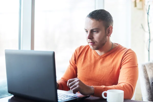 Joven guapo trabajando en el cuaderno, pensando, mientras disfruta del café en la cafetería — Foto de Stock