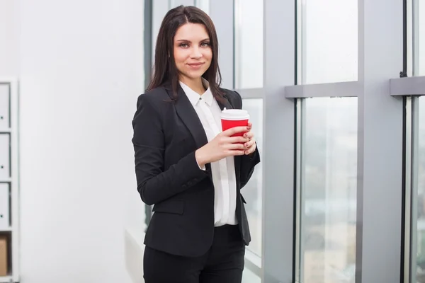 Femme d'affaires debout à la fenêtre avec tasse — Photo