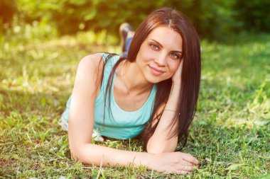 Açık havada mutlu ve gülümseyen çimenlerin üzerinde rahatlatıcı güzel kadın.