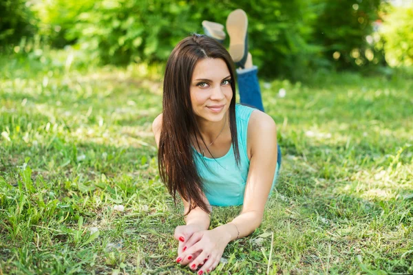Hermosa mujer relajándose al aire libre en la hierba mirando feliz y sonriente . — Foto de Stock